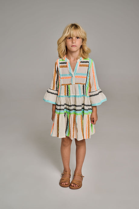 Offwhite dress with colorful jacquard stripes, tiered skirt, and bell sleeves on girl.