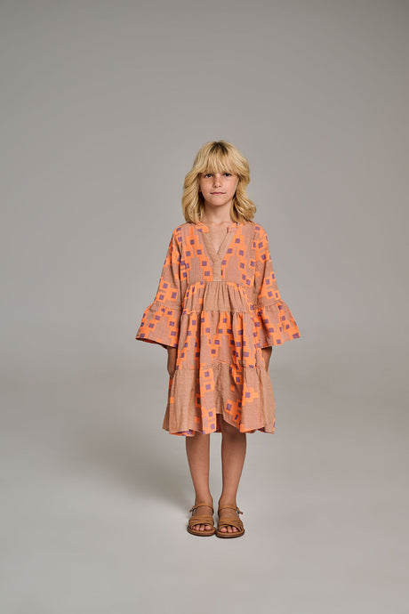 Beige mini dress with orange star print, flared sleeves, and gathered waist worn by child model.