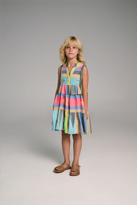 Sleeveless multicolor striped dress with pleated skirt worn by child with sandals.