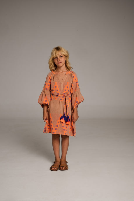 Beige dress with orange star patterns, puffed sleeves, and gathered waist worn with sandals.